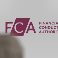 The logo of FCA Financial Conduct Authority on a white wall, in the foreground a blurry passerby.